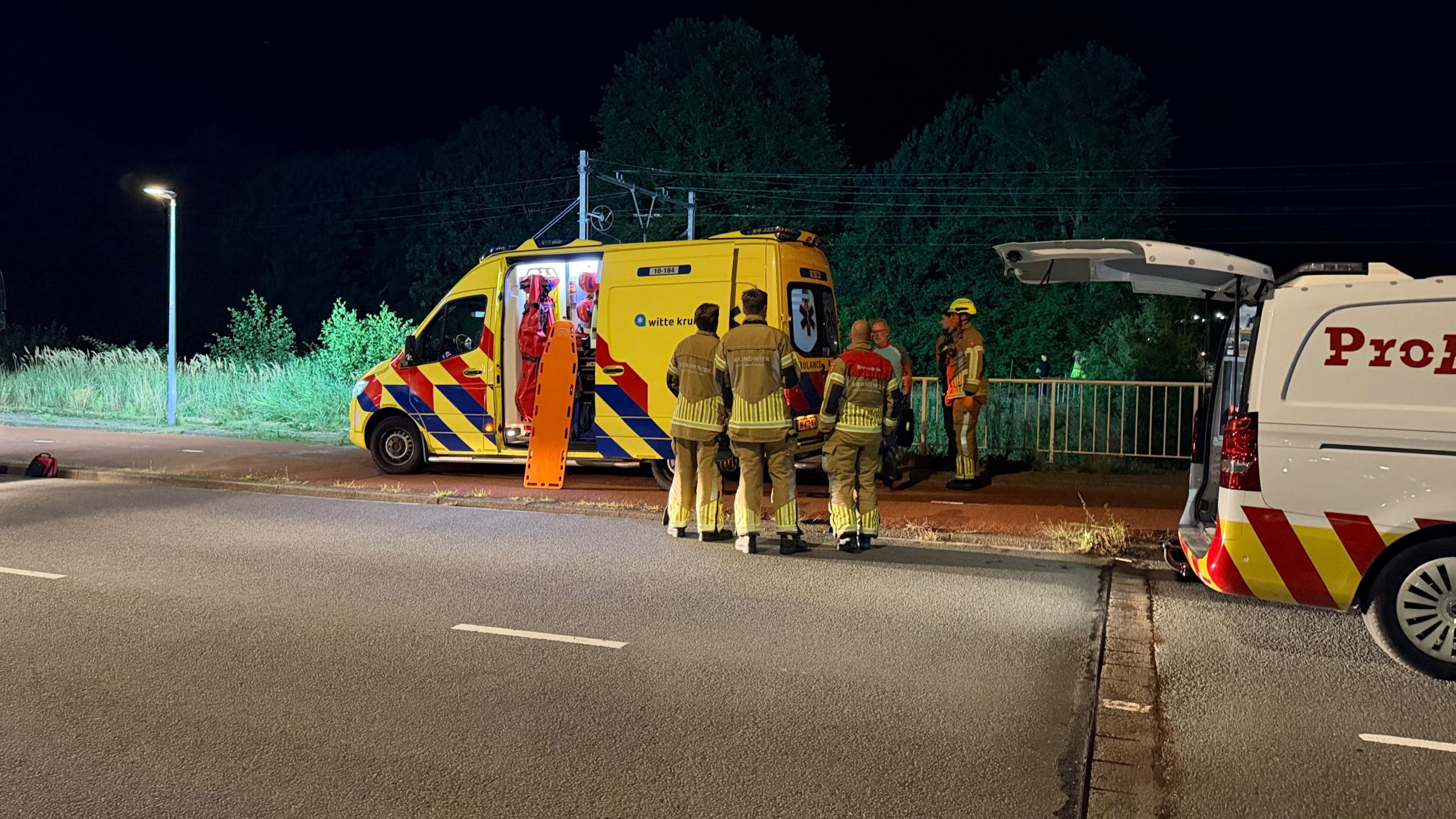 Hulpdiensten met zaklampen bij een spoorlijn langs dicht groen, vermoedelijk tijdens een nachtelijke zoekactie