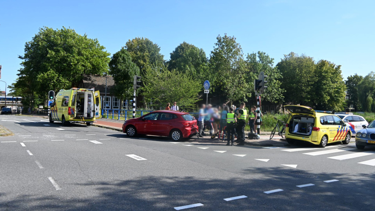 Rode auto op de stoep bij een kruispunt; een omgevallen fiets ligt tegen een paal met oversteekknop