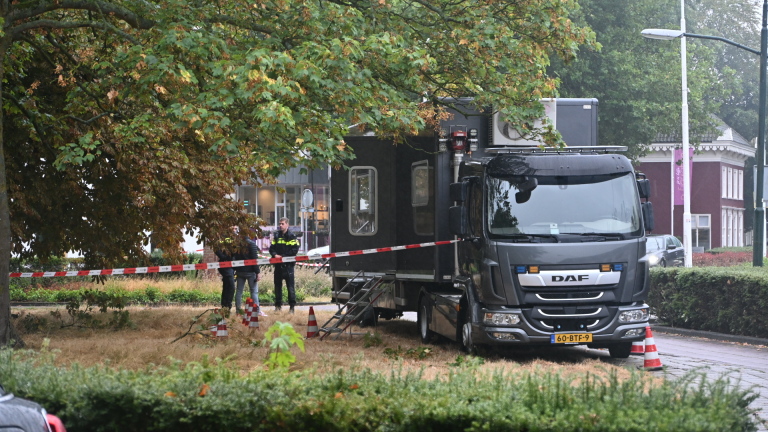 DAF-vrachtwagen bij afgezet gebied met verkeerskegels en rood-wit lint onder bomen naast een parkpad