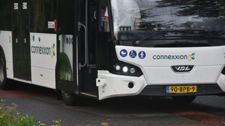 Politieauto met zwaailicht naast stilstaande lijnbus 160; agenten en bestuurder praten op een bosrijke weg