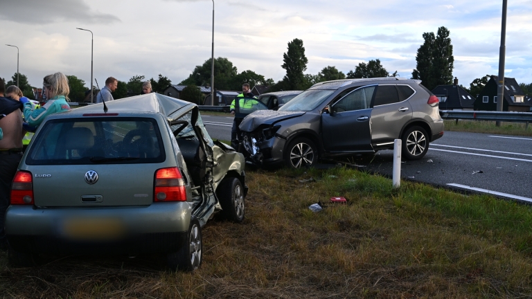 Politieauto met zwaailicht blokkeert rijstrook met pionnen; gele hulpdienstauto en vrachtwagens staan stil in file