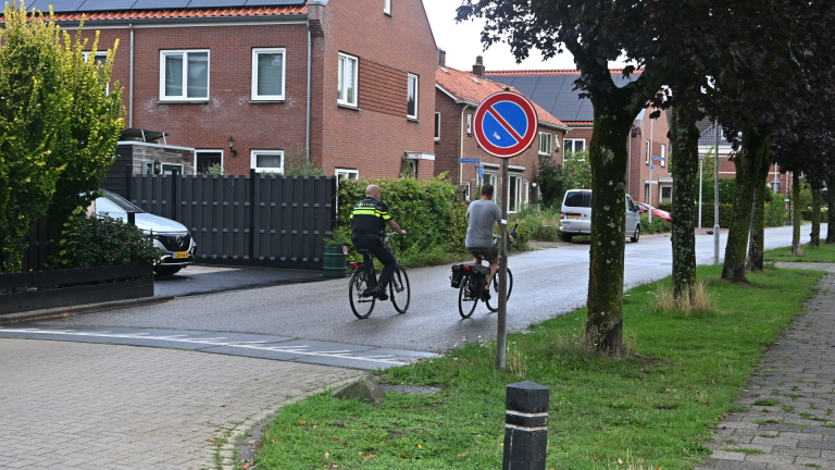 Oranje SUV geparkeerd op nat wegdek met op de achtergrond een gele Witte Kruis-ambulance en omstanders