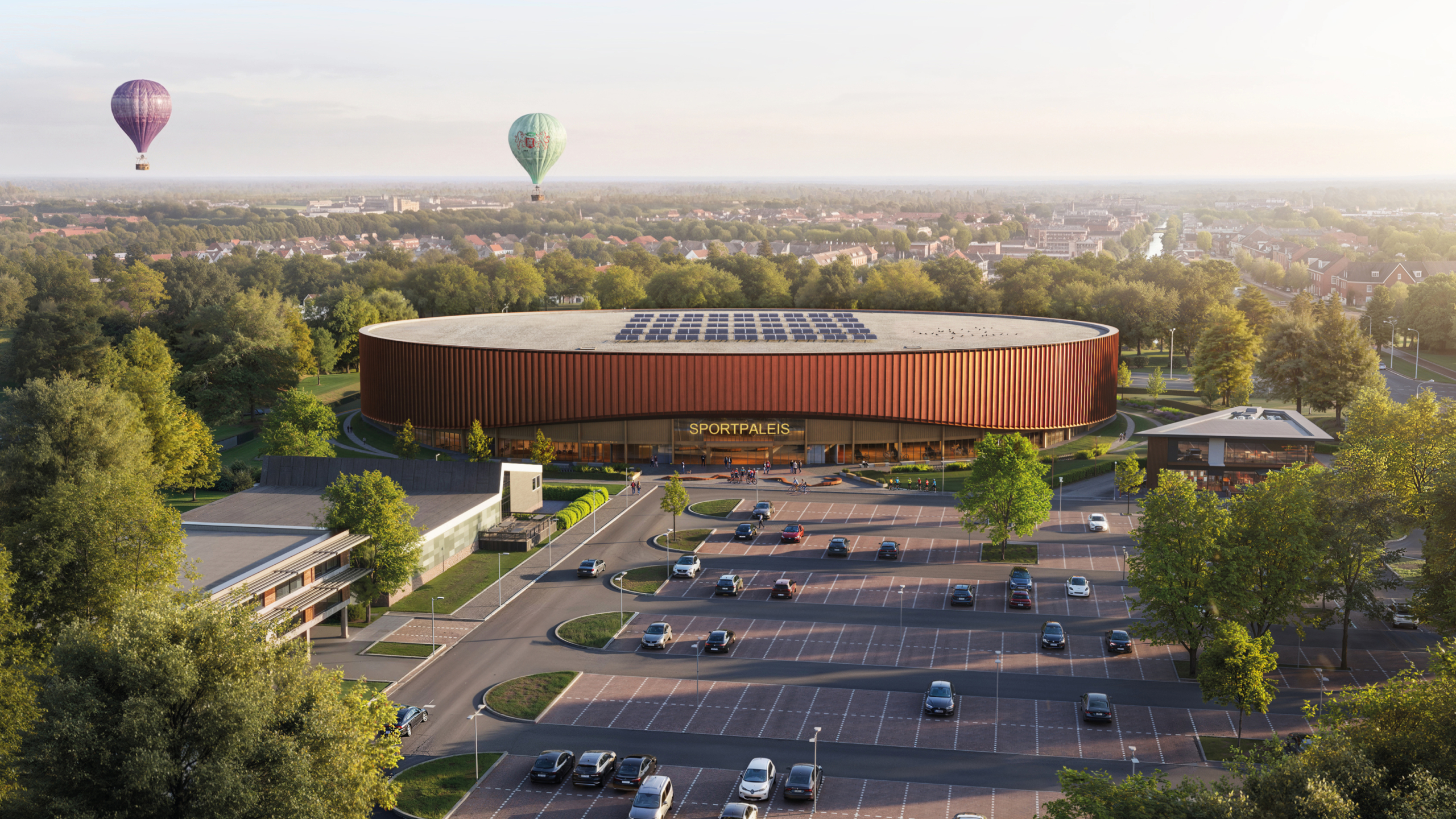 Modern rond sportpaleis met roodbruine gevel, mensen en fietsers bij de entree, omringd door groen en bloemen