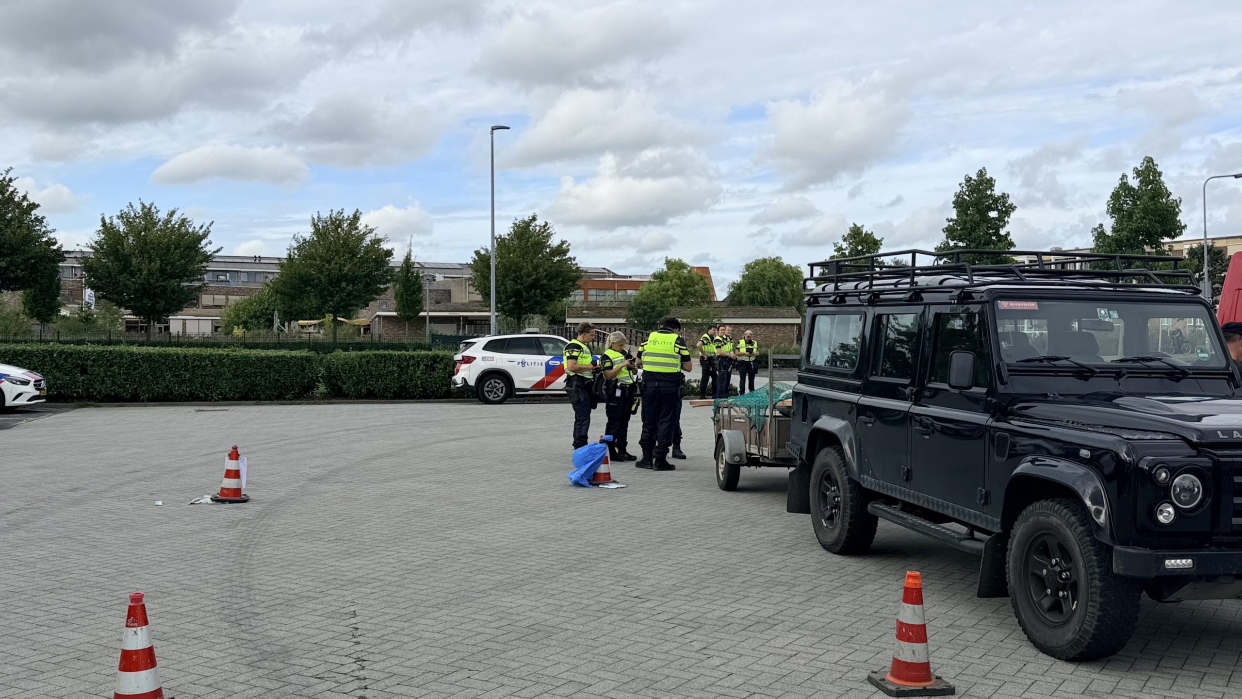 Politieagent op een scooter op een testbank, met politievoertuigen en een caravan op de achtergrond