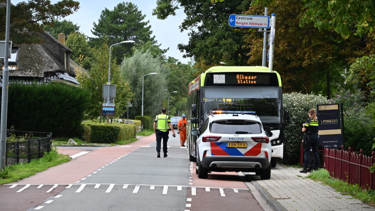 Lijnbus met bestemming Alkmaar Station staat stil bij politieauto en ambulance terwijl hulpdiensten overleggen langs de weg