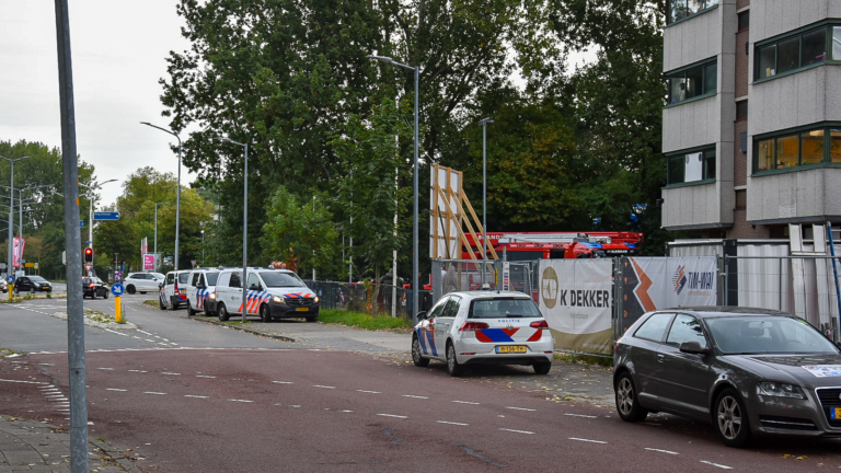 Twee politiewagens en twee ambulances geparkeerd bij een gebouw op een terrein met hekwerk