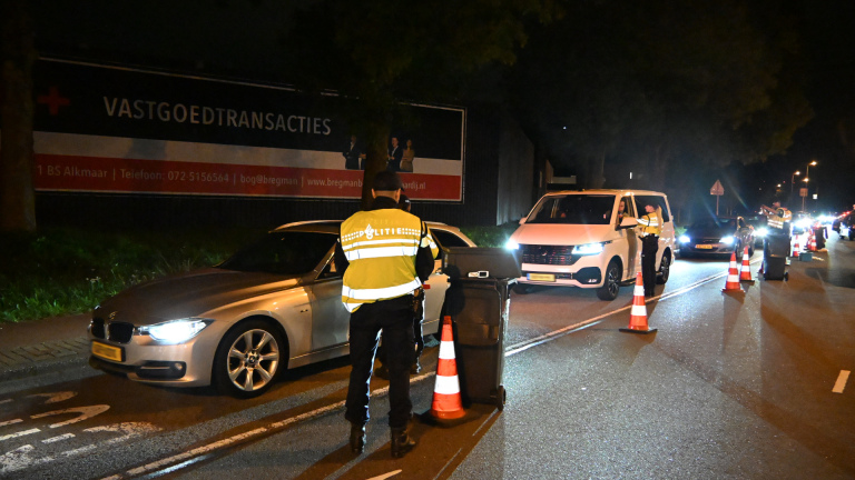 Politiecontrole ’s nachts op de weg, met agenten, verkeerskegels en auto’s die worden gecontroleerd