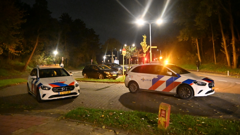 Ambulance in de nacht met geopende deur; drie hulpverleners staan bij het voertuig langs de weg
