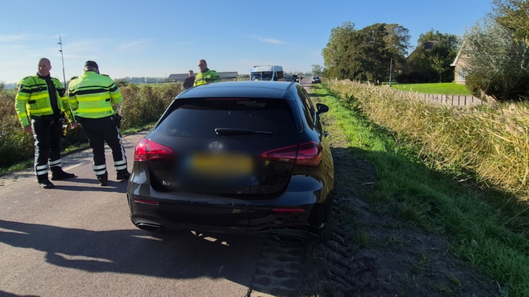 Motorfiets ligt omgevallen tussen hoog riet en gras langs de waterkant, met zichtbaar achterwiel en kenteken