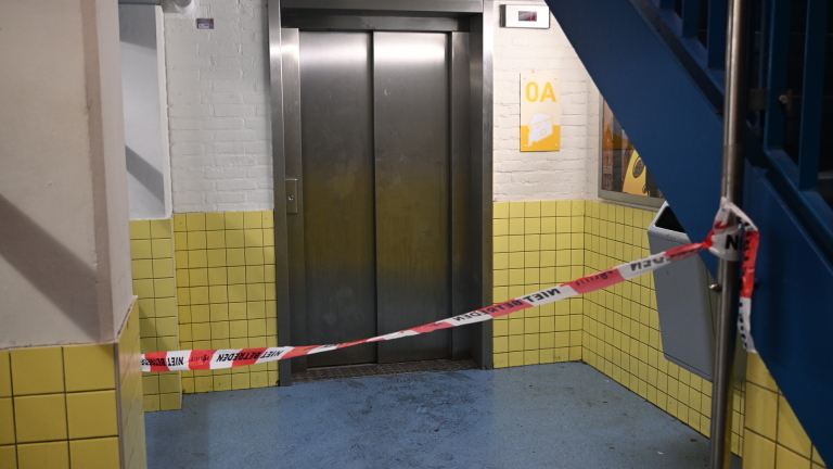 Drie politieagenten staan ’s avonds op een natte straat voor een SPAR-supermarkt, een agent kijkt op zijn telefoon