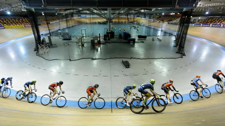 Wielrenners op een indoor wielerbaan in een velodroom.